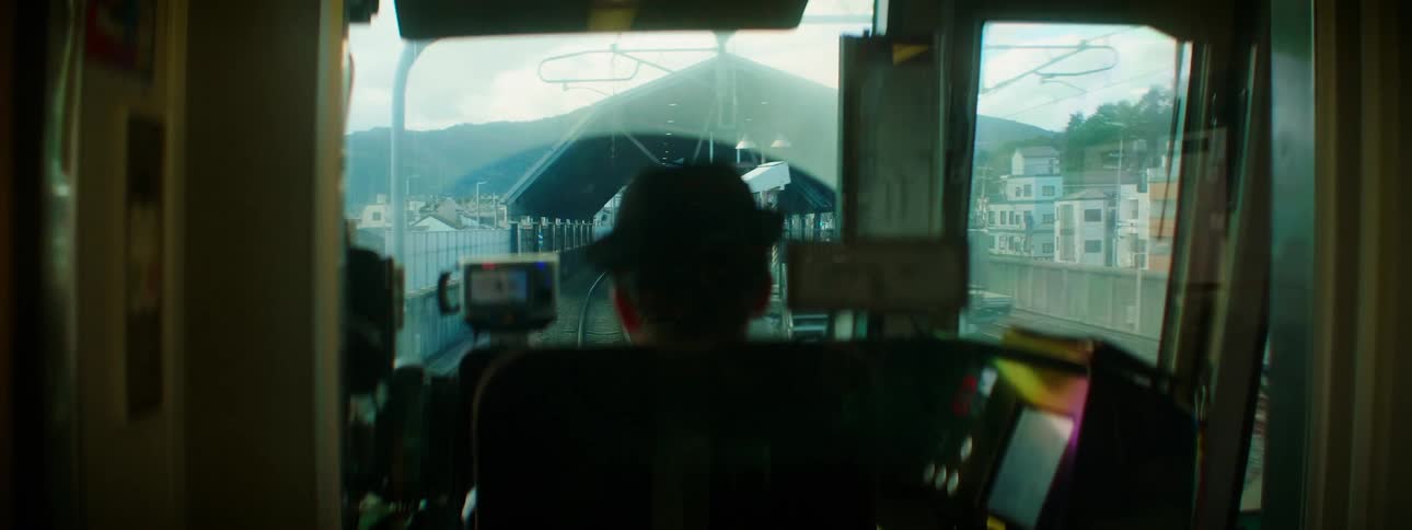 A man drives a train in to a station in a city