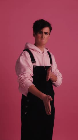 A white male teenager with overalls rubs his hands together
