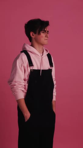 Man stands with hands in pockets on a pink background