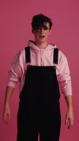 A young teenager stands and talks and motions with his hands