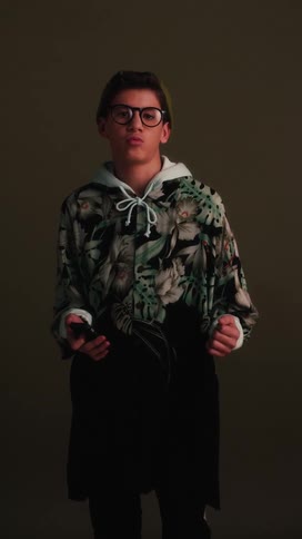 A teenager dressed in odd clothing moves his hands and sways