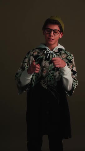 A teenage boy in a costume speaks and moves his hands