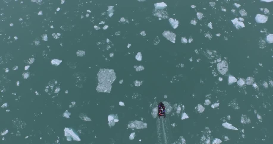 People travelling through icy water in an inflatable boat