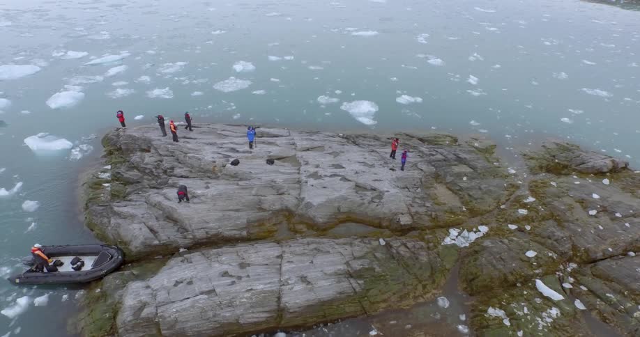 A group of people are standing on an island in an icy ocean