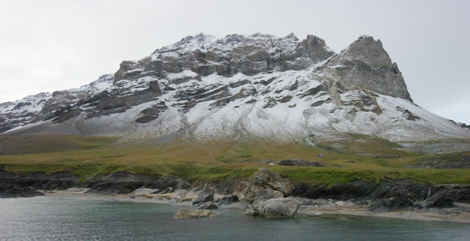 Water flows near a craggy peak dusted with snow