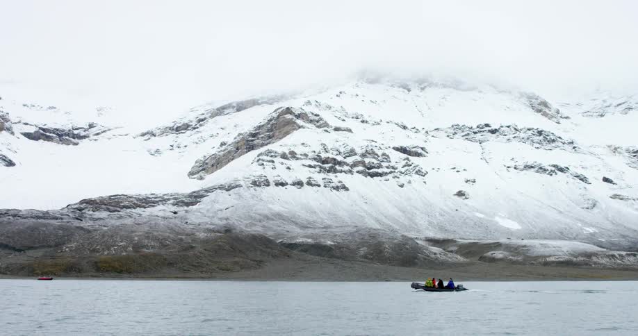 A raft is sailing past a snow covered mountain