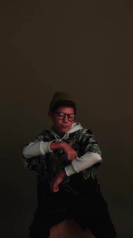 A young boy sits and moves his arms like he is dancing