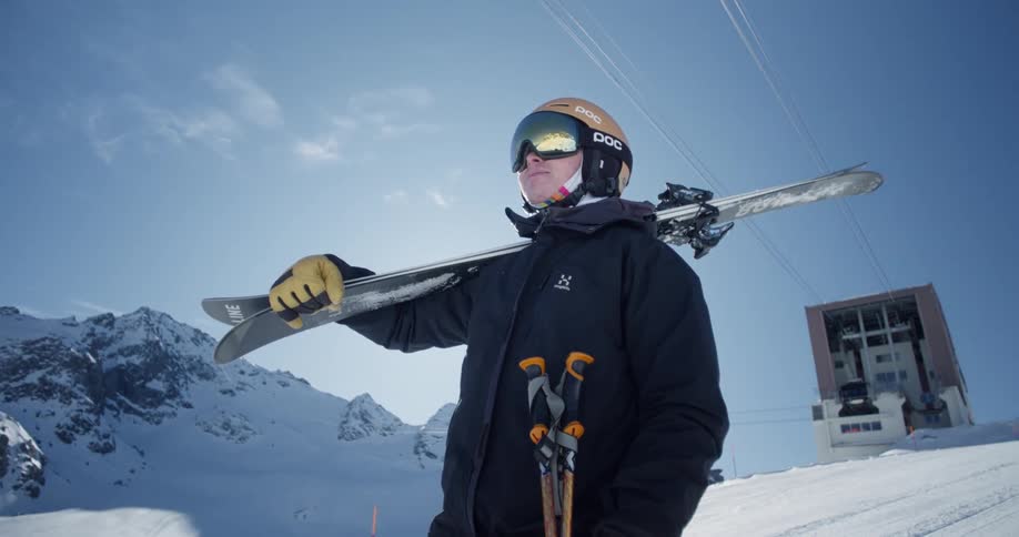 Person standing at top of ski run with skis and poles assessing the run
