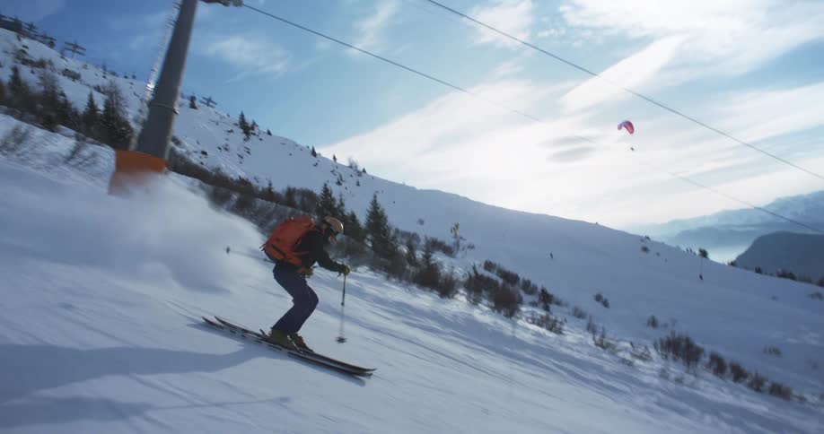 A skier is using their ski poles to make their way down a steep hill as snow flies