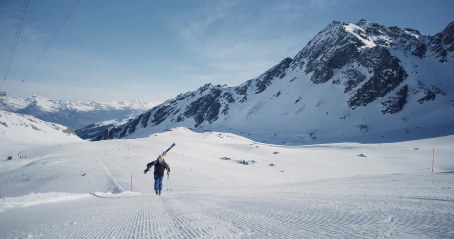 Hiking up a ski hill carrying skis and poles