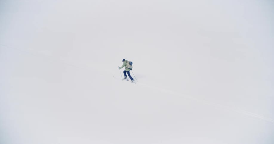 Wide angle view of a lone skier going uphill