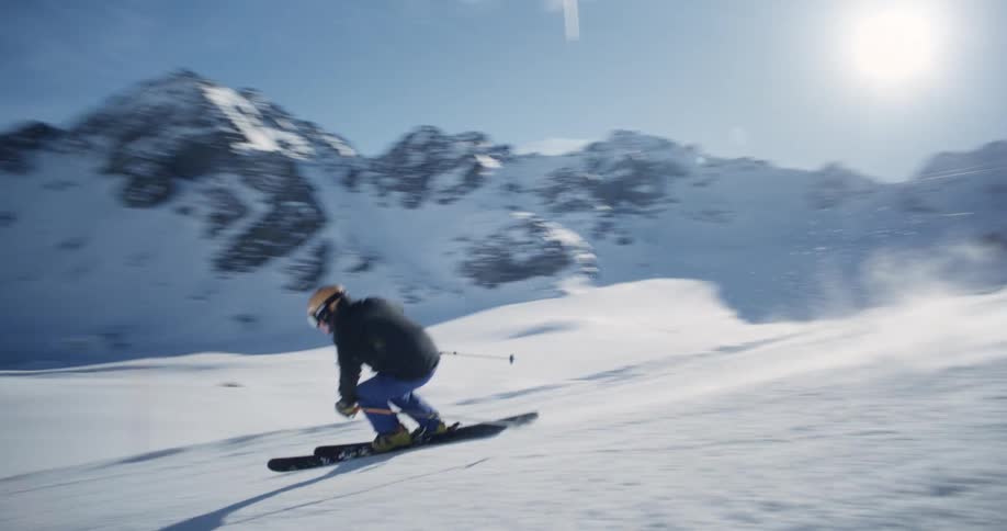 A person skiing down a snowy mountain slope starting from the top and skiing down
