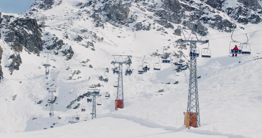 A ski lift carrying people over a snow covered mountain