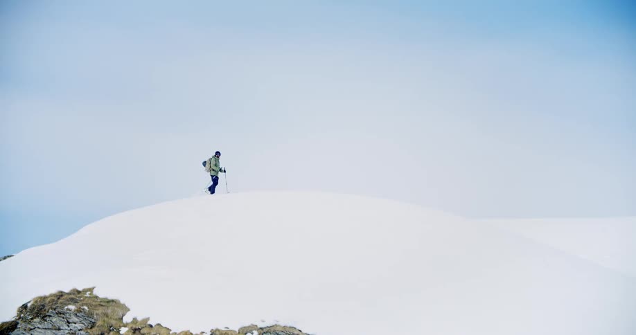 A man hikes across the top of a snow covered mountain