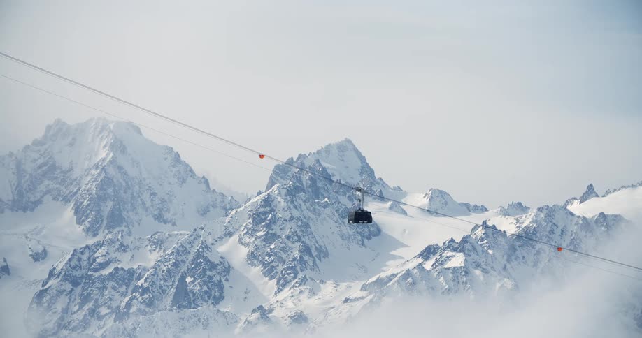 Cable car goes up over the snow covered slopes of a mountain range