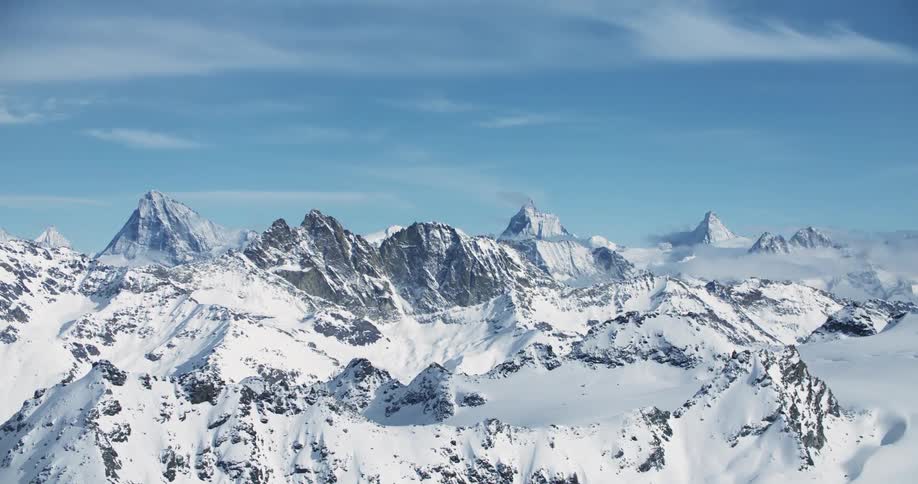 The sun shines on a snow covered mountain ridge