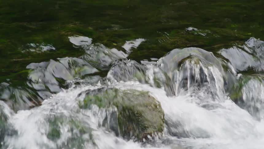 Close up of a river streaming down over rocks covered in moss