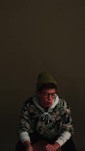 Man wearing glasses sits and moves his arms and head in sync