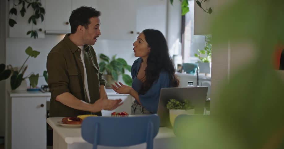 A man and woman have a discussion while standing together in the kitchen