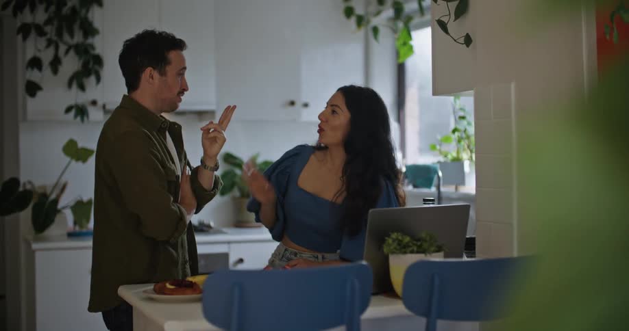 Young couple have a conversation in the kitchen at home while browsing on a laptop