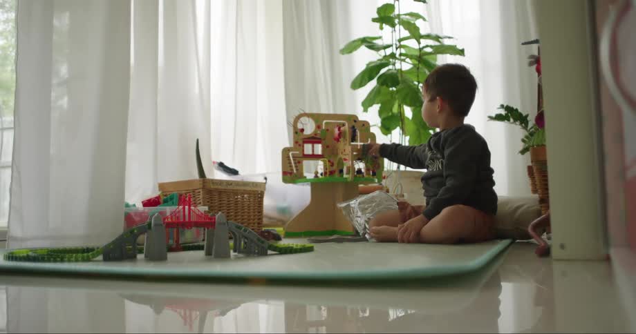Small boy sitting on the floor in living room playing with toys