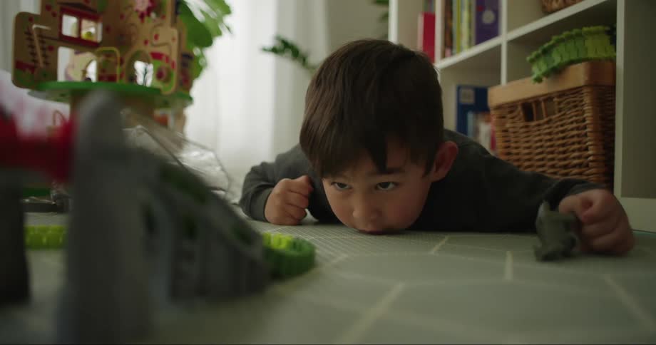 Close up of the face of a boy looking at a toy car moving on a track