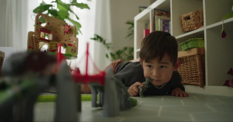 A boy watches as a toy goes around a toy track
