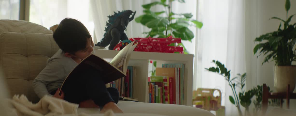 Boy sitting on the couch at home reading a story book