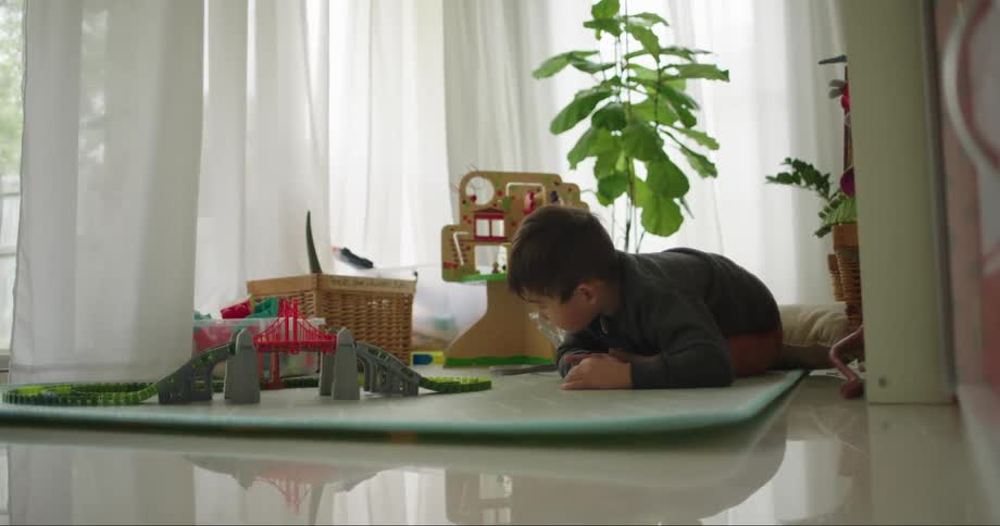 Little boy in play room playing with train set on the floor during the day