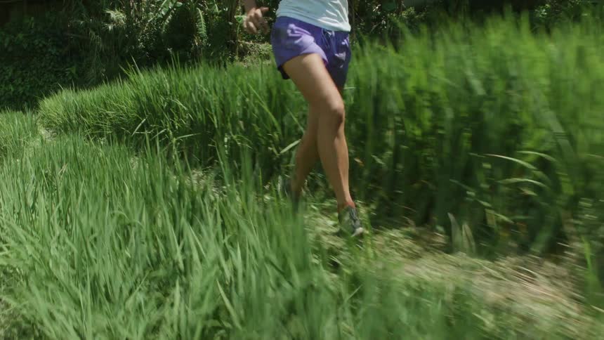 A woman running in tall grass on a beaten down path