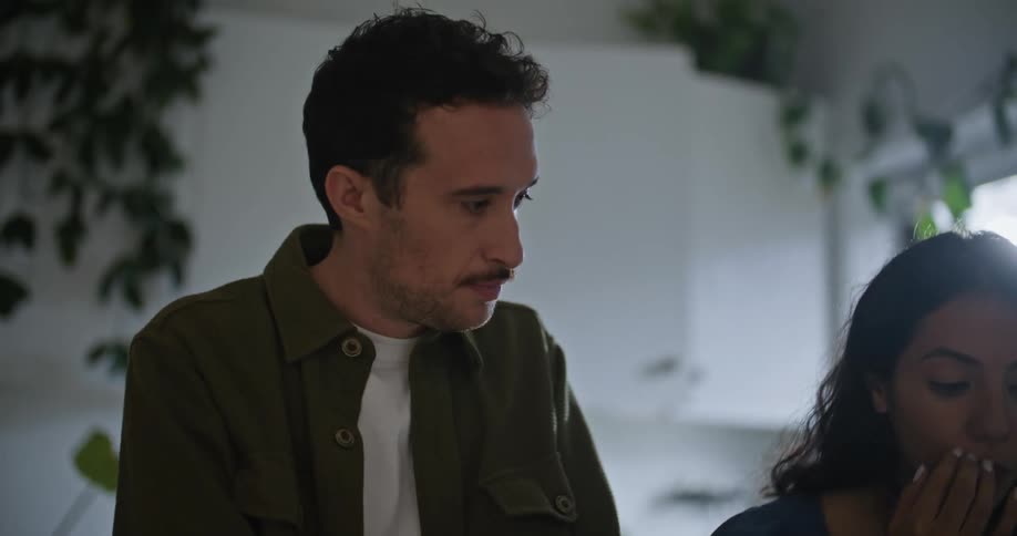 Young couple have a conversation while looking at a piece of paper in the kitchen at home