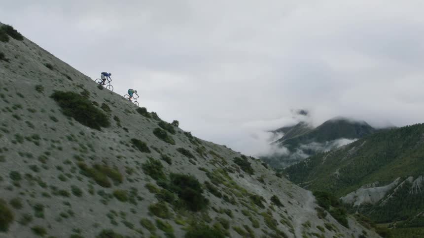 Two cyclist pedaling downhill on the slope of Nepalese mountain at daytime
