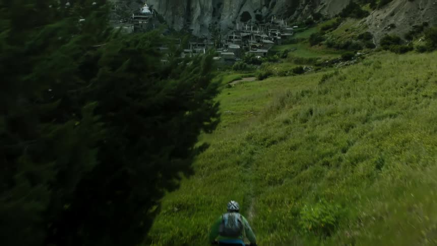 Two cyclists pedaling on a road on the hills near a village in the mountains