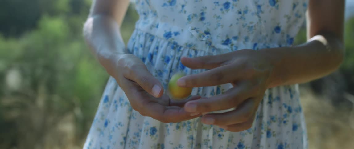 A womans torso as she holds a yellow ball in her hands passing back and forth