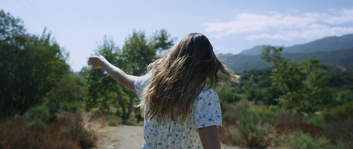 A woman is walking outdoors in a wooded area during spring