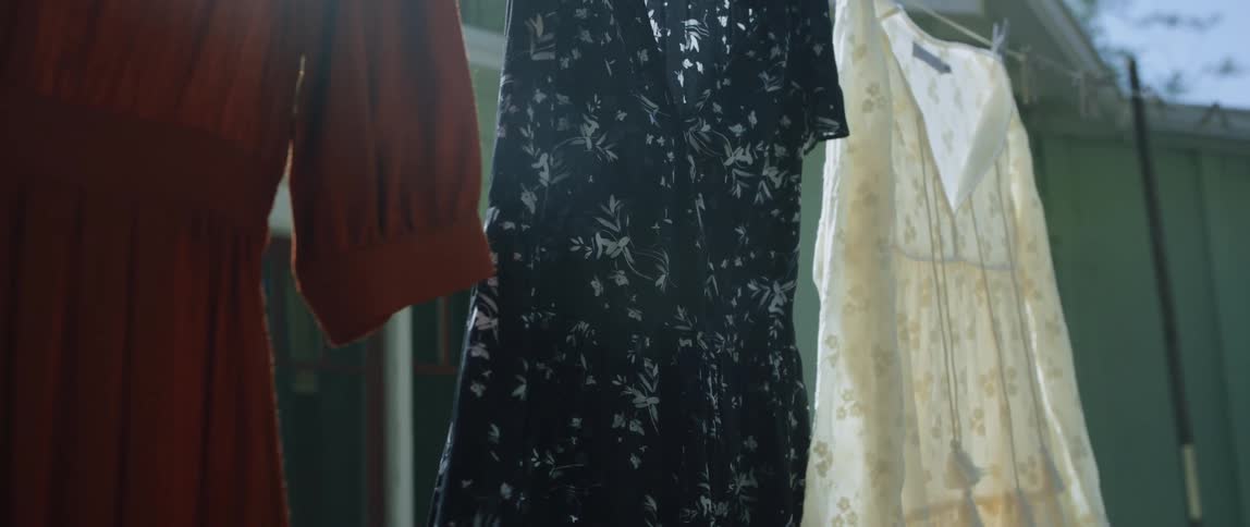Female clothing dries on a clothesline hanging outdoors during the day