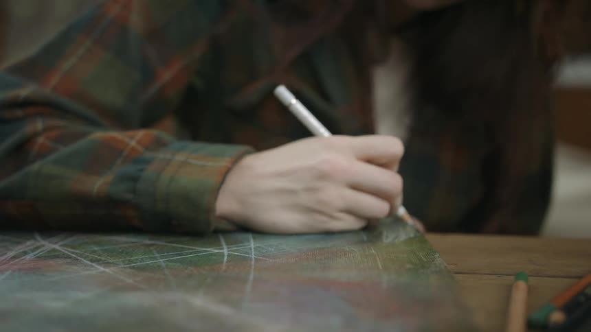 A woman sketches on a piece of cardboard