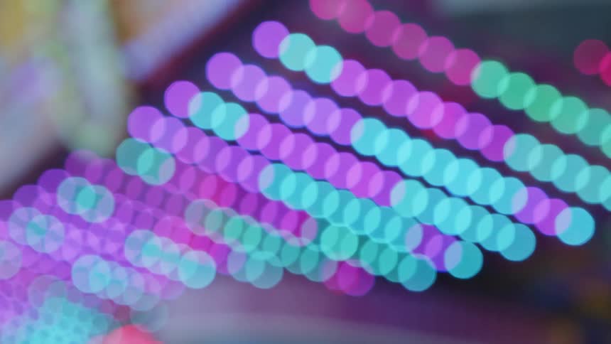 Out of focus close up of bright colorful alternating lights on the ceiling of an attraction in the amusement park