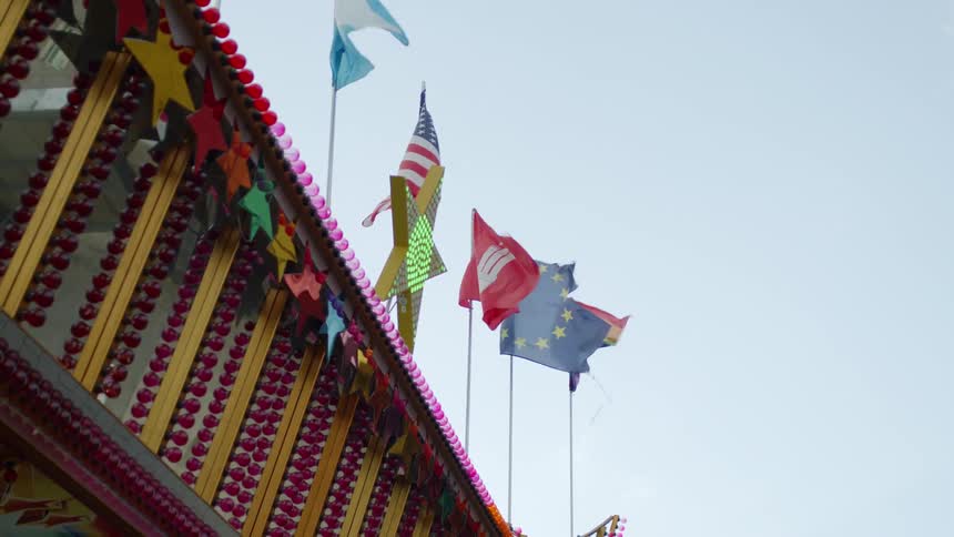 Various flags waving on the wind over an amusement park at daytime