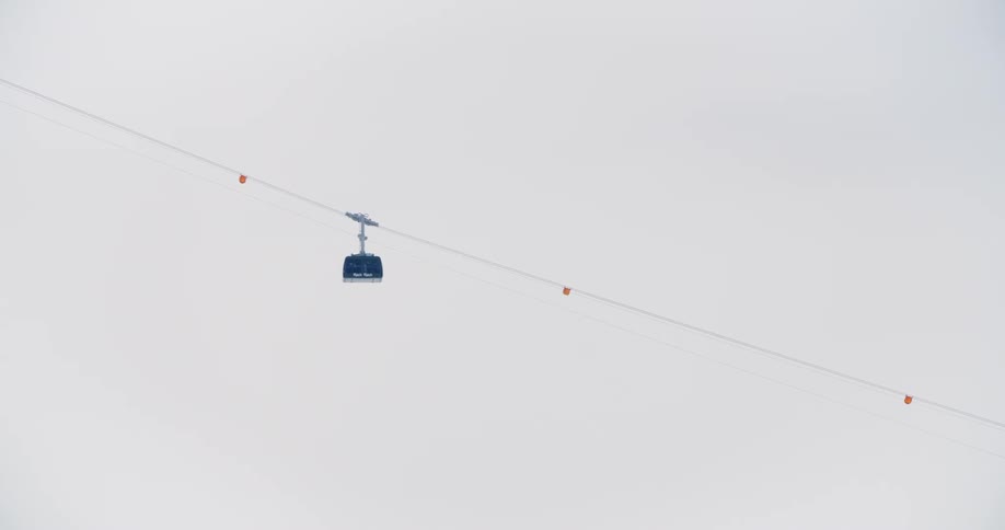 Wide view of ski lift or zip line ascending mountain whiteout