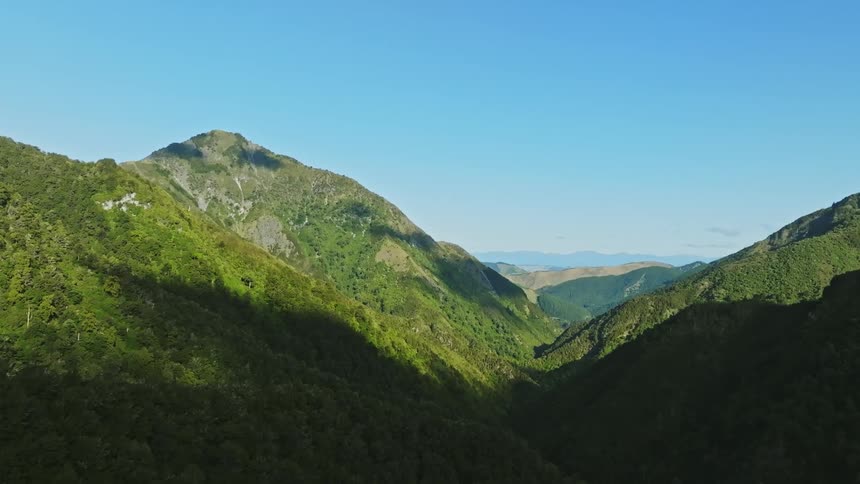 Shadows cover portions of forest covered mountains in range