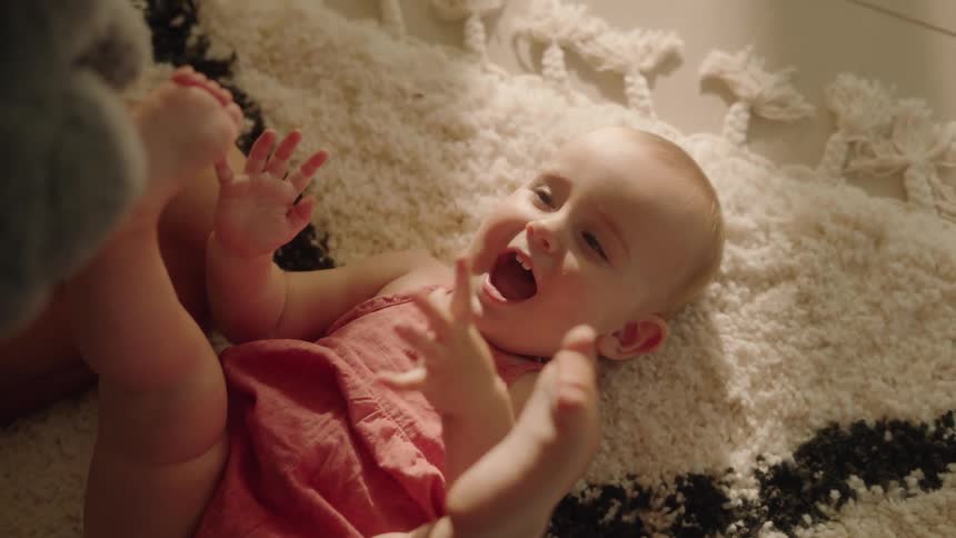 Dad playing with baby and stuffed animal on the floor baby is giggling