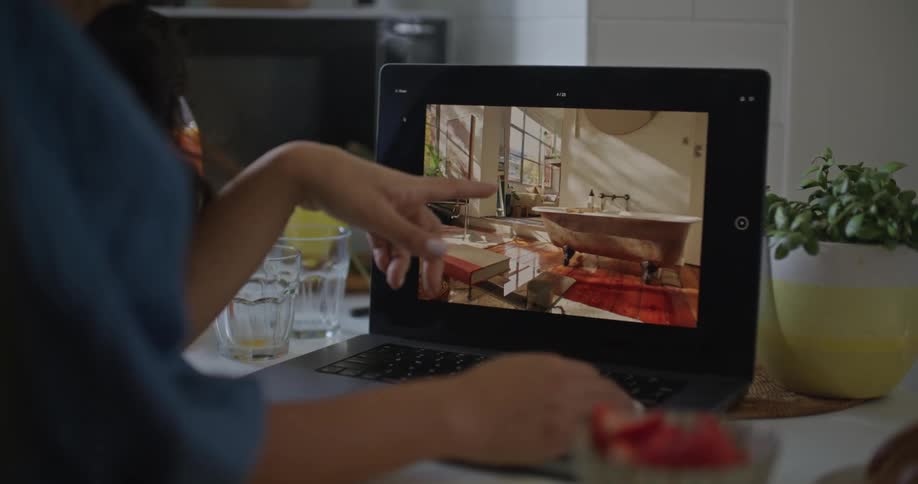 A close up of a woman sitting in front of a laptop screen pointing at it as she talks