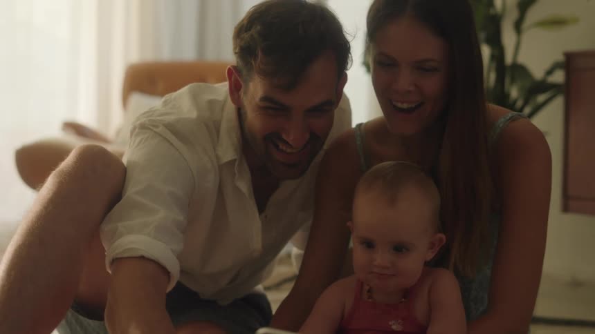 A family sits on the floor together to take a selfie with a phone