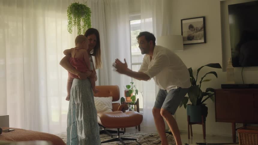 Parents dancing with their daughter in the living room at home