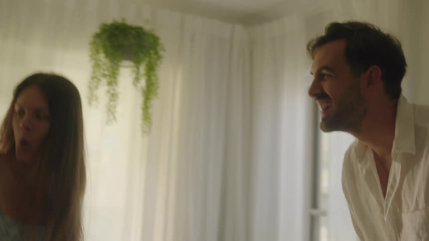 Father is dancing in front of his wife and baby as they move around with him in their living room