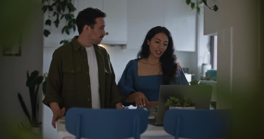 A man and woman have an animated conversation while looking at a laptop