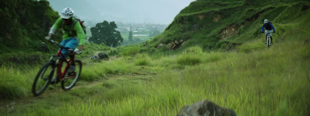Mountain biking across a trail on a grassy field on a mountain