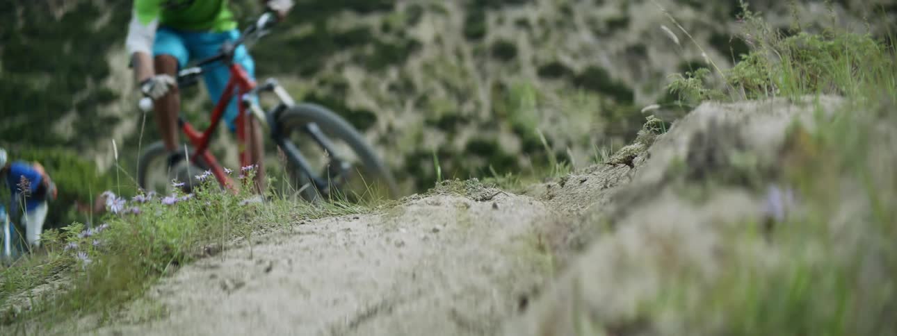 Close up of the wheel of a bicycle kicking dust while driving on a dirth path