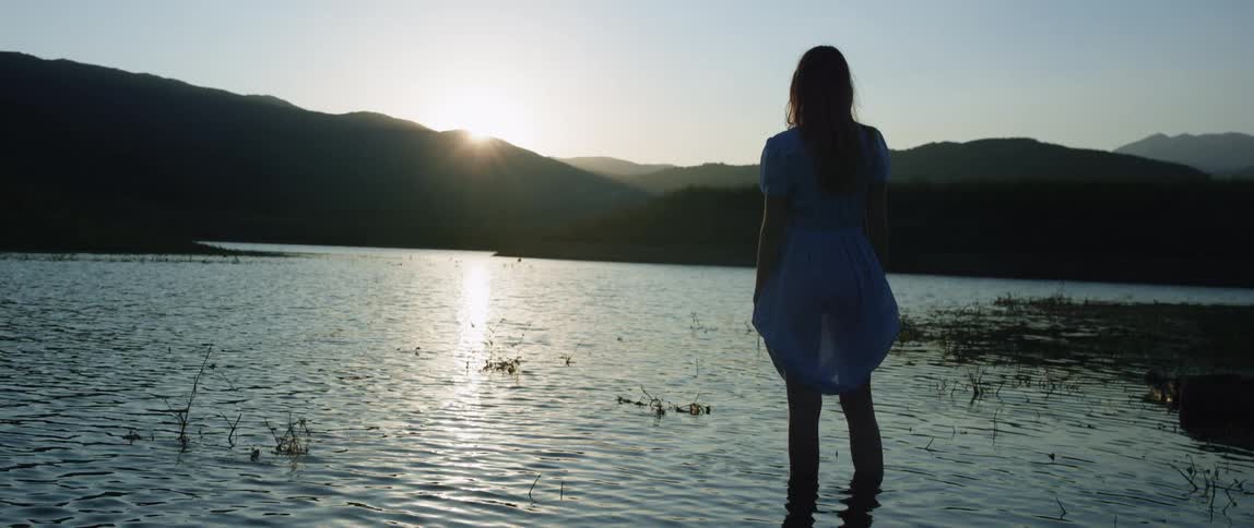 Woman standing in a lake at sunrise looking out at the landscape enjoying the view